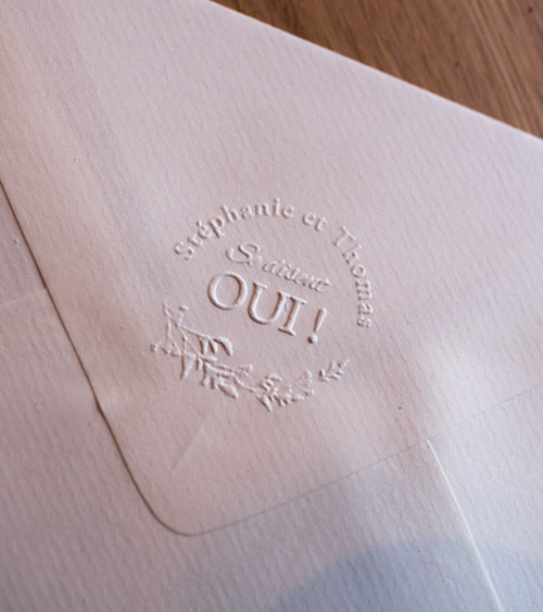 Embossage des faire-parts de mariage avec une pince personnalisée.